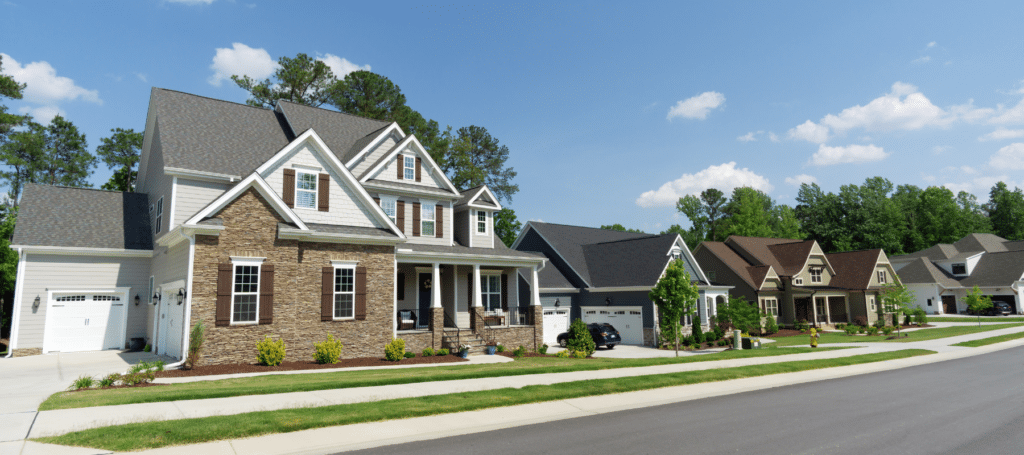 A row of modern suburban homes with well-maintained lawns under a bright blue sky