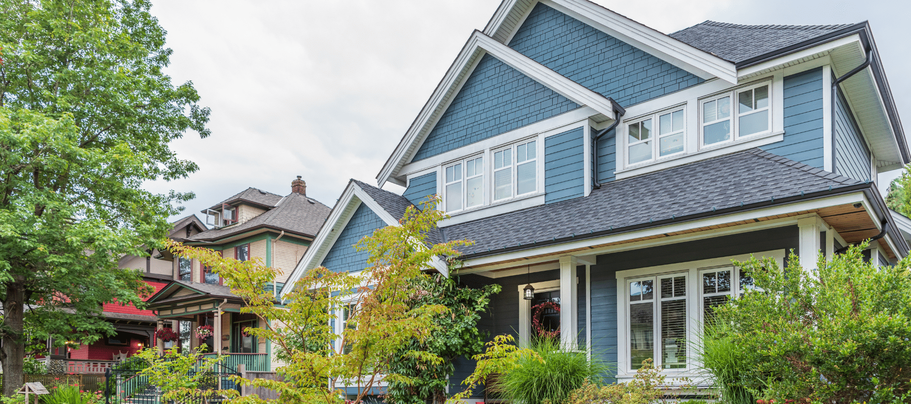 A beautiful blue home with lush greenery and a well-manicured front yard